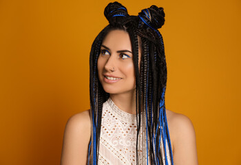 Beautiful young woman with nose piercing and dreadlocks on yellow background