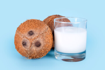 Coconuts and a glass of coconut milk on blue background. Healthy vegan food, lactose free diet,...