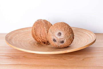 Whole coconuts on the plate on natural wooden background.