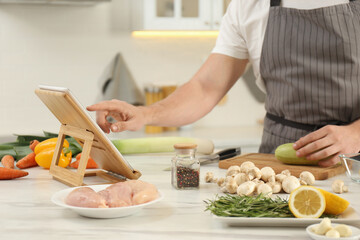 Man watching online cooking course via tablet in kitchen, closeup