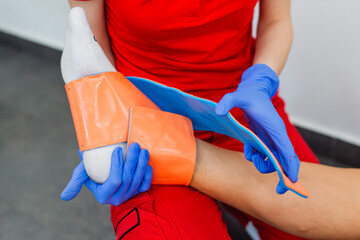 Close-up of female doctor bandaging foot of patient at doctor's office. First aid