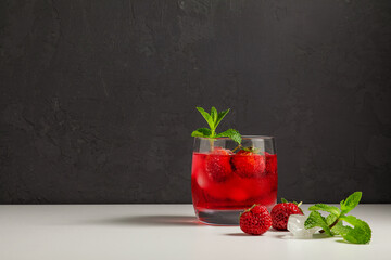 cold, homemade, strawberry lemonade with ice in glass glasses, mint leaves and berries on a dark background