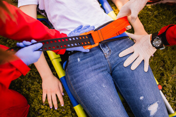 Paramedics put her on a stretcher and take care of a woman injured in a car accident. First aid training. Closeup