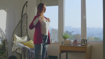 Young woman trying on new clothes while spending free time at home