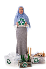 eco living and environment concept - full length of smiling asian muslim woman in hijab with plastic and glass bottles, paper garbage in boxes holding recycling symbol, isolated over white background