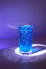 Closeup image of shining cocktail with shimmer at blue minimal background with reflections.