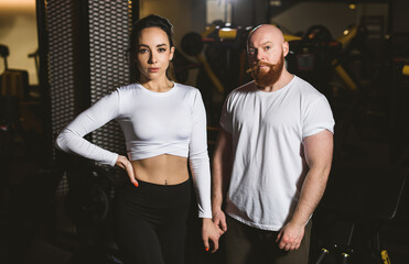 Portrait of a sports couple. Young trained woman and muscular guy. Trainer and ward in a sports club.