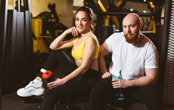 Portrait of a sports couple. Young trained woman and muscular guy. Trainer and ward in a sports club.