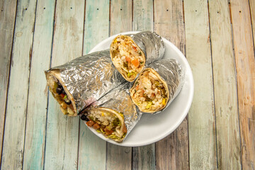 Two huge burritos halved and rolled with aluminum foil - obrazy, fototapety, plakaty