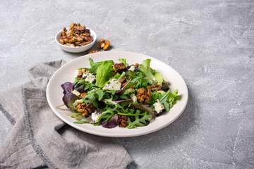 Healthy vegetarian salad with mix of fresh green leaves, blue cheese and walnuts