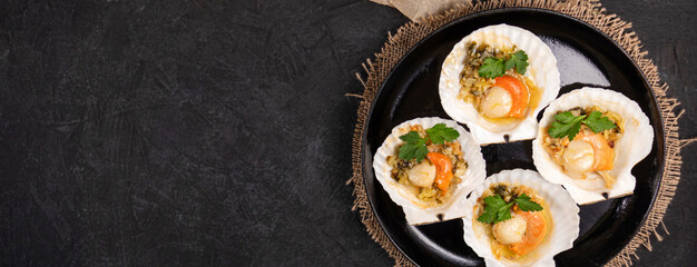 banner with flat lay of baked scallops with caviar and creamy garlic sauce on a black textured background with space for your text. Top view.