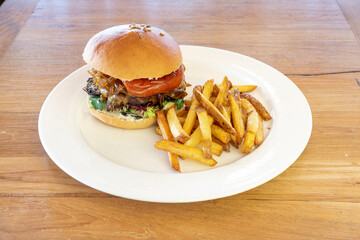 Amazing hamburger with fried pepper, caramelized onion, sunflower seeds, lettuce sprouts and French fries with skin