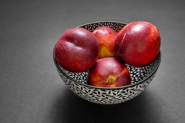 Fototapeta na wymiar Nice Bowl with black and white color full of ripe red nectarines ready to eat