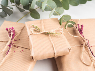 Fototapeta na wymiar Wrapped gift boxes in craft paper with dried flowers decor