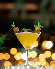Yellow cocktail on blurred background with bokeh. a glass with a tropical alcoholic or non-alcoholic drink shot. Vertical format. Copy space.