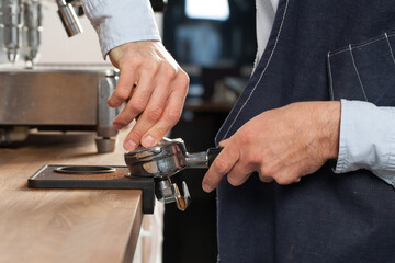 Barista pressing fresh coffee grounds in a cafe, selective focus