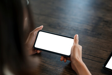 Close up shot of a woman holding a smartphone horizontally blank white screen. Mock up.