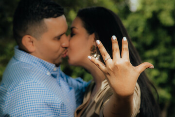 pareja de latinos besándose mostrando anillo de compromiso en primer plano 
