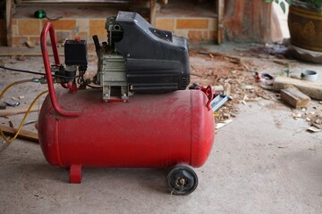Old red air pump machine at construction work site. Concept : mechanic's tool. Useful for various works, build, repair , fix and maintenance. Use in industrial family. garage, and factory. - obrazy, fototapety, plakaty