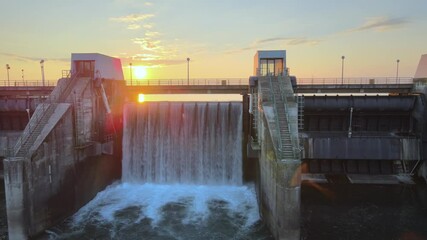 Water flowing at speed when gates of water reservoir at hydroelectric power plant are opened. Golden hour, Close up sliding view.