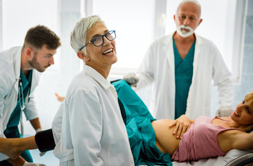 Obraz premium Woman giving birth in hospital with medical doctor team