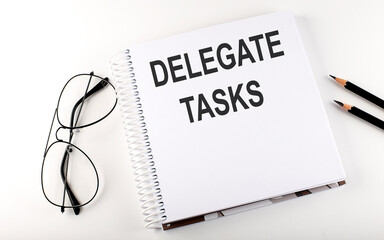 Notebook with text DELEGATE TASKS on the white background