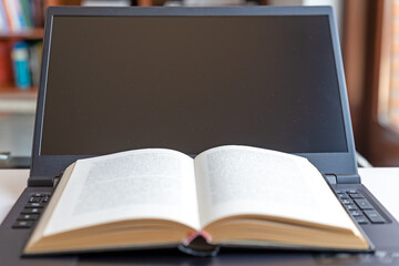 Notebook computer, with books placed on the black keyboard. E-learning and remote lessons.