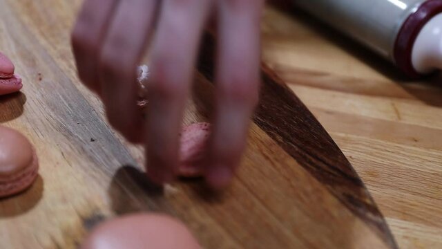 Teenage girl makes macarons in the kitchen. Close-up shoot on piping out pink mixture.