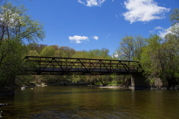 Straight River and Pedestrian Overpass with bright blue sky and clouds at River Bend Nature Center.