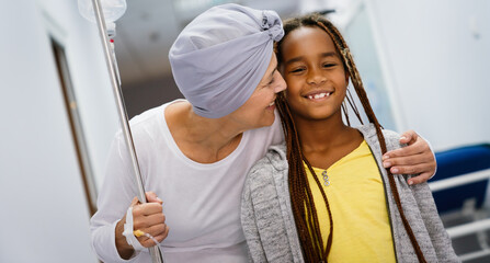 Sick woman with cancer hugging her young grandchild in hospital. Family support concept. - obrazy, fototapety, plakaty