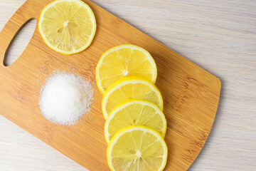 Lemon slices and white granulated sugar on a wooden kitchen board. Lemon is a cure for colds. Side...
