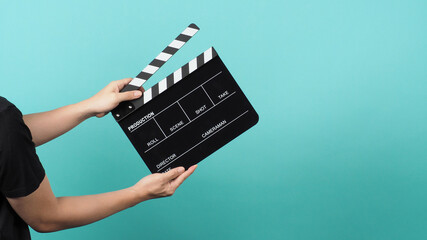 Hand is holding Black clapper board or movie clapperboard or slate on green mint or Tiffany Blue...