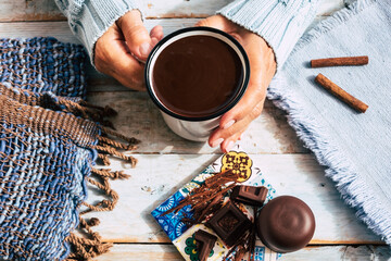 Cup of hot chocolate in woman's hands and pieces of chocolat on wooden rustic table