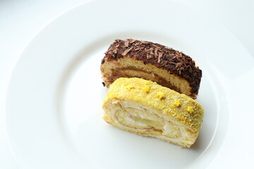 Slice of chocolate and lemon roll cake on a white plate 
