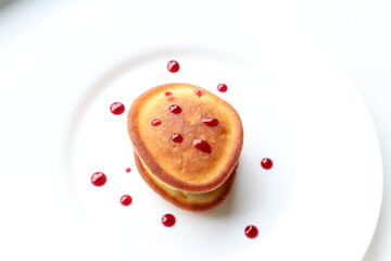 Pancakes with cherry syrup on a white plate 