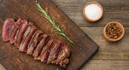 classic beef steak uncooked meat ,fried outside, red inside, with red juice, cut into pieces on a wooden board