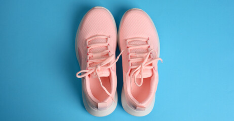 pink women's sneakers with laces on a blue background, top view