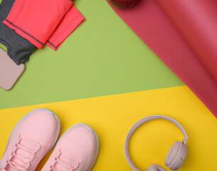 red sports mat pair of pink sneakers, wireless headphones, a smartphone on a green yellow background