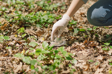 Volunteer woman is cleansed in the forest. Woman collects plastic. Woman volunteer with a bag with the inscription - No more plastic.