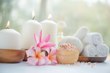 Obraz na płótnie Canvas Natural relaxing spa composition on massage table in wellness center with towels, flowers and salt, candle on massage table in spa salon.