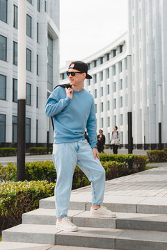 Young Free Beautiful Fashionable Hipster Guy Walking Down The Street, Wearing A Cap Sunglasses, Urban Style