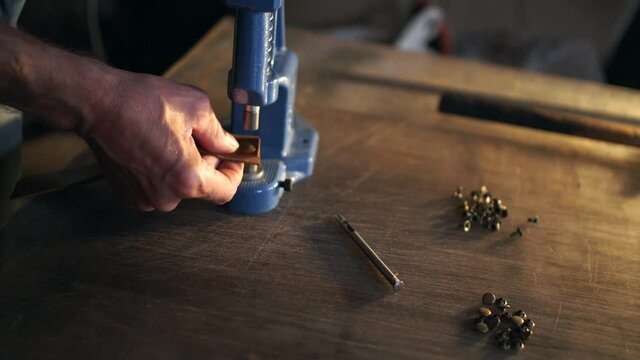 Professional skinner working with leather in workshop.