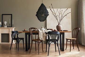 Stylish rustic interior of dining room with walnut wooden table, retro chairs, decoration, fireplace, dried flower, candlestick mock up picture frame and carpet in minimalist home decor. Template.