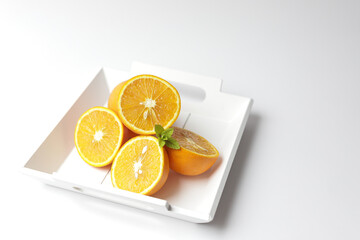 Cut oranges in white wooden plate.