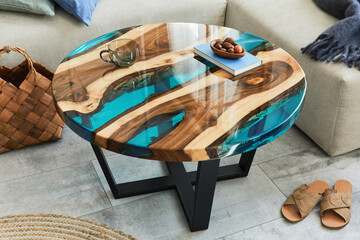 Stylish composition with design epoxy coffee table, sofa, blanket, pillows, book, decoration and personal accessories in modern home decor. Template. Details.