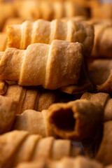 Lots of sweet home made confectionery tubes prepared to be filled with cream. Photo taken under soft artificial light.