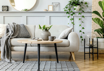 Scandinavian living room interior with design grey sofa, wooden coffee table, tropical plants,...