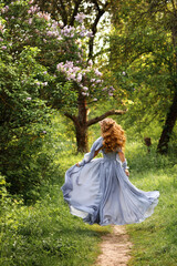 Girl in lilac dress runs away in summer garden
