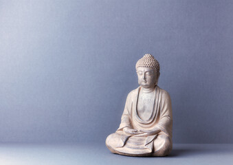 Fototapeta na wymiar Meditating Buddha Statue on paper background. Copy space. 
