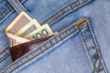 Wallet and lots of Polish banknotes sticking out of the back pocket of denim pants. Photo taken under artificial, soft light